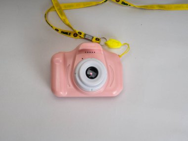 Beyaz arka planda pembe bir kamera oyuncağı.