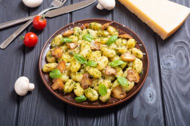 Ahşap arka planda fesleğen, peynir ve mantarlı ev yapımı patates gnocchi.