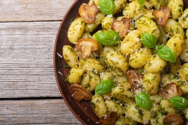 Ahşap arka planda fesleğen, peynir ve mantarlı ev yapımı patates gnocchi.