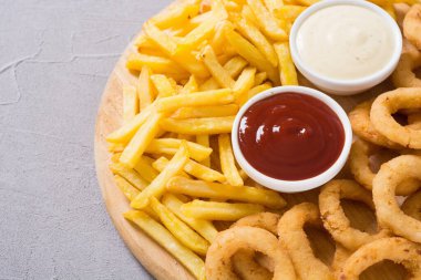 Tahtada soslu patates kızartması ve soğan halkaları.