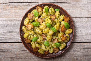 Ahşap arka planda fesleğen, peynir ve mantarlı ev yapımı patates gnocchi.