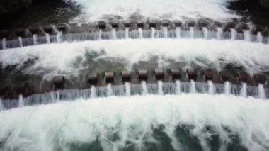 Ormanda süzülen bir dereyle uçan bir dron görüntüsü.