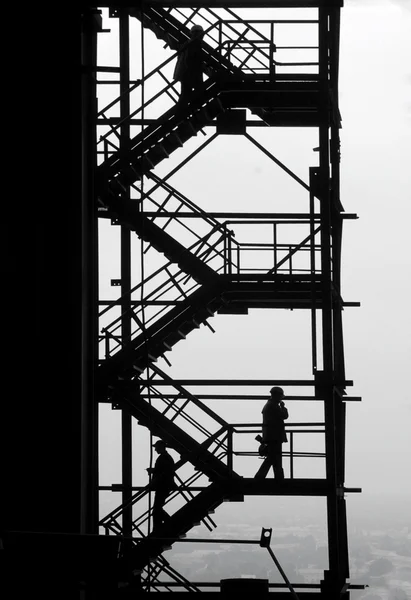 Silhouette di persone a costruzione industriale alta — Foto Stock