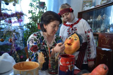 Vashkivtsi, Chernivtsi Oblast, Ukraine - 14.01.2013: Ukrainian craftswomen decorate the mask for Malanka holiday. clipart