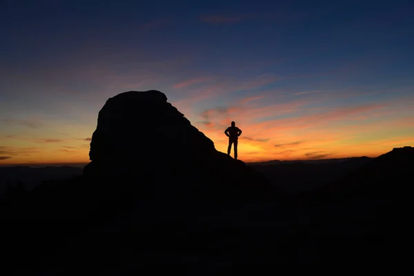 Silhouette of rock and man against morning (sunrise) sky background.