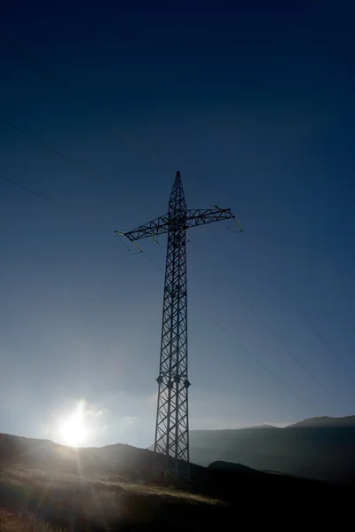 Linha de alta tensão de energia pilão e sol da manhã — Fotografia de Stock