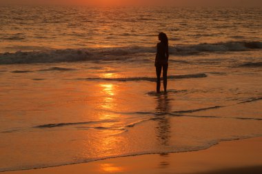 Sundown kadının siluet ile okyanus kıyısında