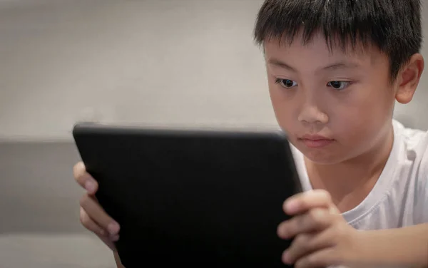 Asian boy playing game on digital tablet at home , Children watching cartoons on digital taplet or smartphone