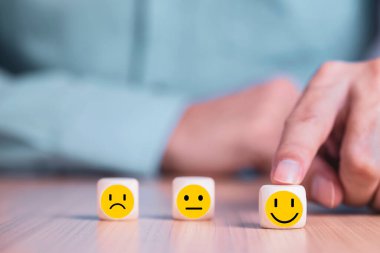 İş adamı bir gülümseme simgesi seçti: Ahşap blok, Hizmetler ve Müşteri memnuniyeti anketi konseptinde mutlu simgelerle karşı karşıya