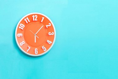 beautiful Orange wall clock on blue background ,concept of Start the morning to work.