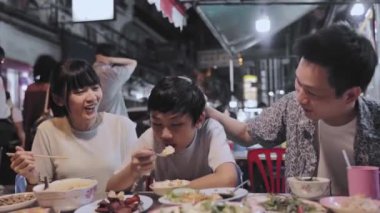 Asyalı aile, Bangkok 'taki Yaowarat Yolu' nda Çin Mahallesi 'nde turistler için gece marketinde yemek yiyor.