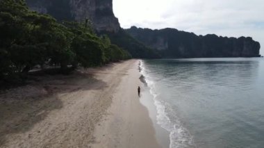 Gün doğumunda kumsalda koşan kadın koşucunun hava görüntüsü ve beyaz kum arka planı.