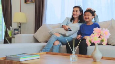 Asyalı bir aile evdeki kanepede televizyon seyrediyor.