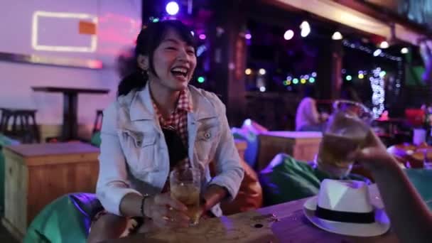 Asijští přátelé paří s holkama v nočním klubu a připíjejí si na pití. Šťastné mladé asijské lidi s koktejly v pouliční hospodě.