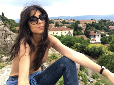 Şehrin üzerinde oturan güneş gözlüklü güzel esmer kadının portresi. 