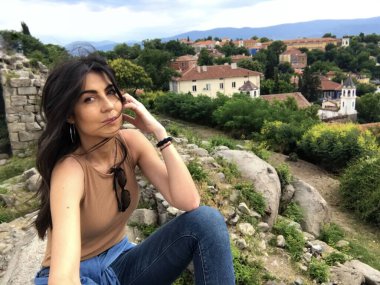 Şehrin üzerinde oturan güneş gözlüklü güzel esmer kadının portresi. 