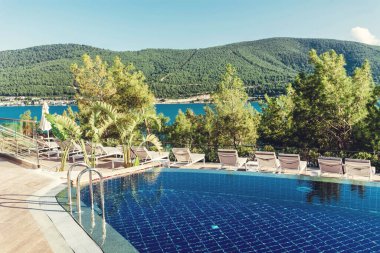 Denizin üstünde dağ manzaralı lüks bir havuz.