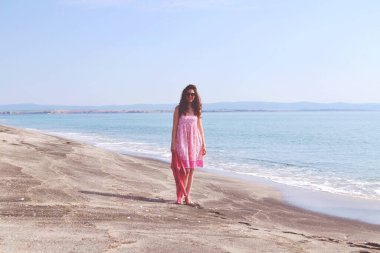 Plajda güneş gözlüklü genç bir kadın. Siyah Kum ve Sakin Deniz. Vintage Efekti 