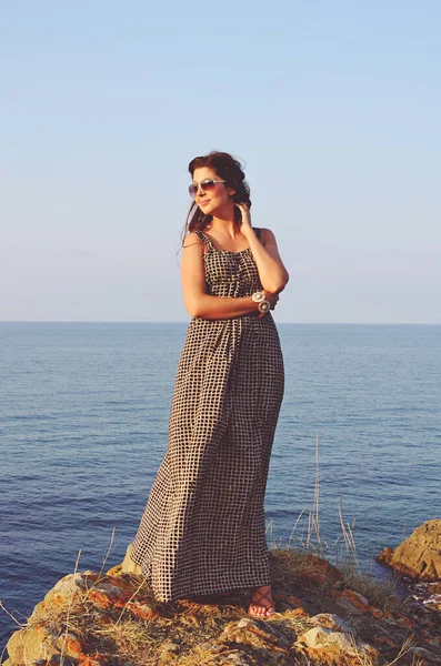 夕日の海の背景にドレスを着た美しい若い女性 — ストック写真