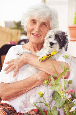 Mutlu kıdemli kadın evinde Havan Köpeğini kucaklıyor.