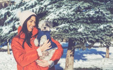 Güzel bir kadın kış ormanında sevimli havan köpeğine sarılıyor. Evcil Hayvan ve Sahibi Açık Hava