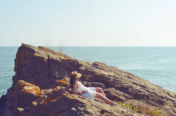 年轻女子坐在海面上的岩石上 — 图库照片