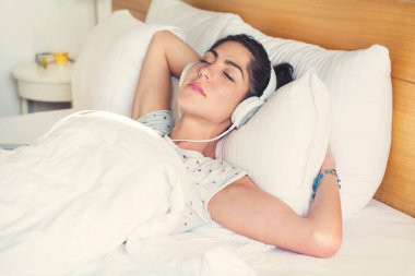 Young Woman Listening Music in the Bed