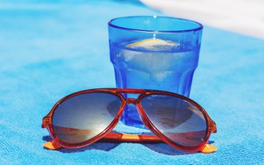 Su, limon dilimi ve turuncu güneş gözlüklü bardak.