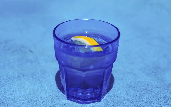 海を背景に水とレモンのスライスを持つガラス — ストック写真