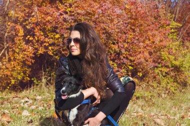 Güz Parkı 'nda evlatlık köpeğini kucaklayan güzel genç bir kadın.