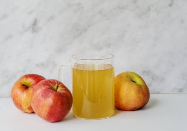 Beyaz arkaplanda elma sirkesi ve kırmızı elmalar