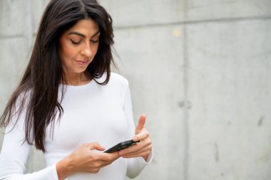 Güzel bir kadın telefonunu açık havada kullanıyor.