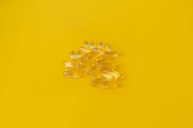 Yellow transparent capsules with medicine on a yellow horizontal background. Selective focus. Concept for your mockup and project. Layout, copy space. 