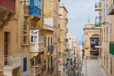 Valletta, Malta. Geleneksel Malta balkonları ve deniz manzaralı eski kasaba sokağı, Valletta şehri.