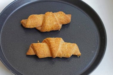 Pişirme tepsisinde iki tane Fransız kruvasanı.