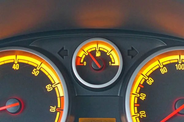 Analog car dashboard fuel gauge with yellow lights