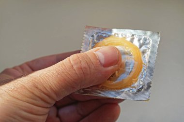 Folyo paketi kondomu elinde tutan adam.