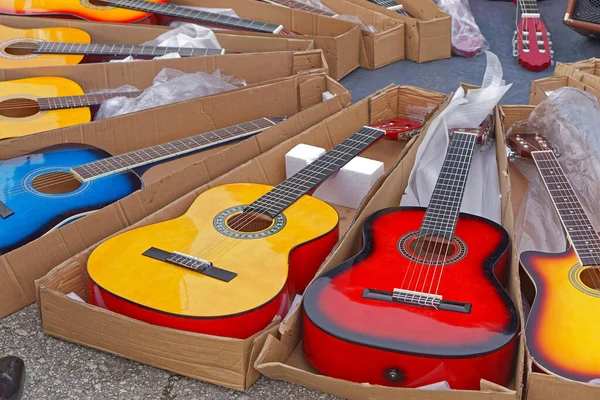 Many new colorful guitars music instruments in boxes for sale