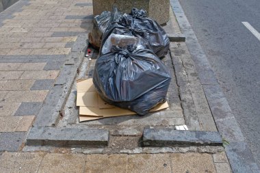 Sokak çöplüğünde bir sürü siyah çöp torbası.