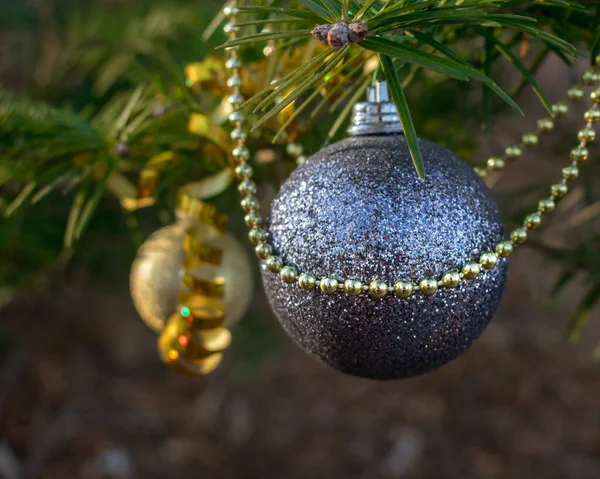 Shiny silver and gold christmas decorations on forest tree