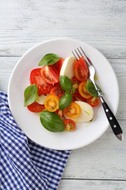 Ahşap arka plan beyaz tabakta Caprese salatası
