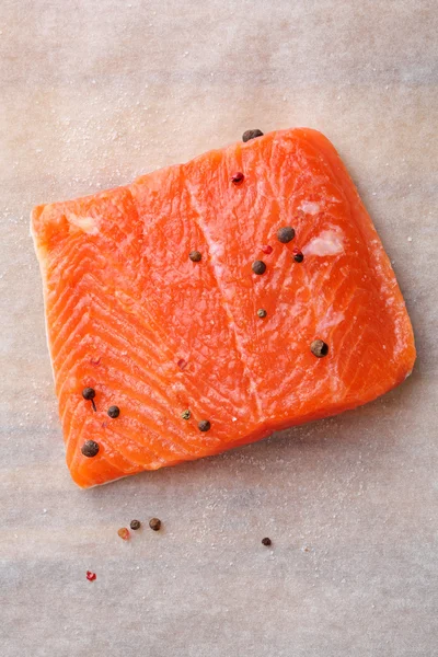 Raw salmon steak with pepper on paper — Stock Photo, Image