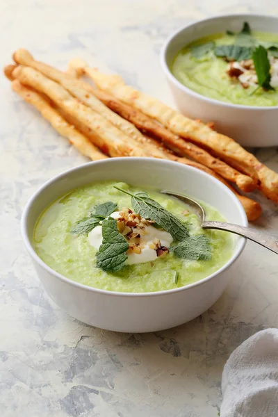 Bowls of zucchini cream soup and bread sticks — Stock Photo, Image