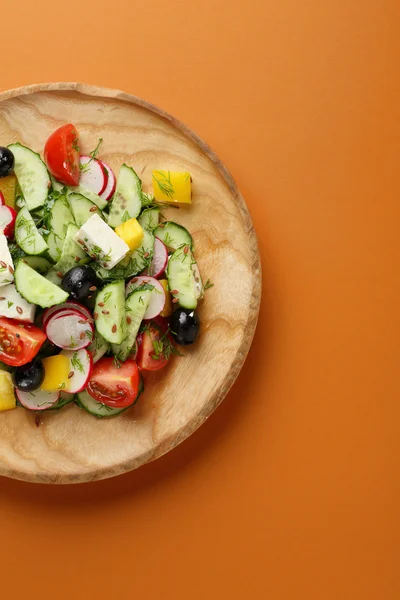 Salade de légumes avec feta sur assiette en bois — Photo