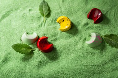 Yeşil kum üzerinde çikolata şekeri ve yapraklar