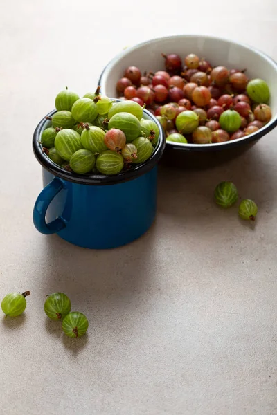 Sluiten Van Groene Kruisbes Blauwe Emaille Mok Stenen Tafel — Stockfoto