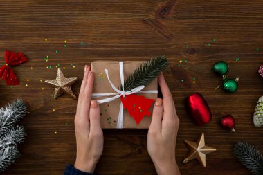 Mevcut kutu ellerde ve Noel süsleri ahşap arka planda.