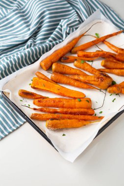 Fırın tepsisinde kızarmış havuç ve mutfak tekstili.