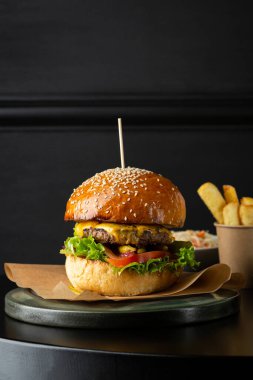 Siyah masaya hamburger ve patates kızartması koy.