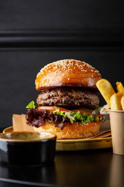 Hamburger yakın, patates kızartması siyah masada.